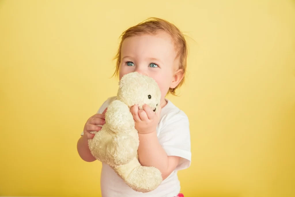 caucasian little girl children isolated yellow studio background portrait cute adorable kid baby playing with teddy bear